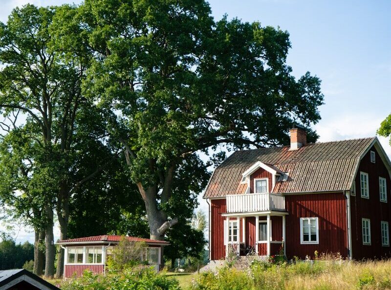A red house sitting on top of a lush green field